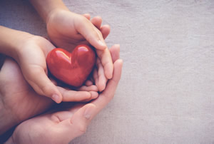 Hands holding a red heart shaped object