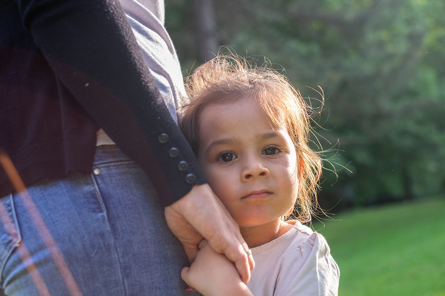 A young girl holding an adult's hand, looking at the camera